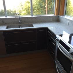 Muebles de cocina en gris con acentos en plata; encimera de piedra natural